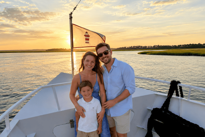 Family on a boat at sunset with a flag in the background.