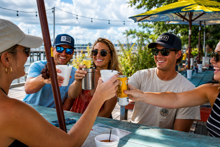 Group of five people toasting drinks at an outdoor table.