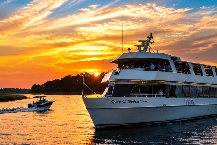 Boat and yacht on water at sunset with colorful sky.