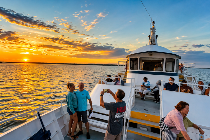 People on a boat enjoying a sunset over calm water.