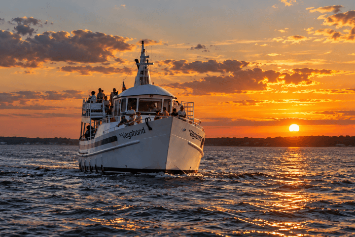 Boat on the ocean at sunset with cloudy sky.
