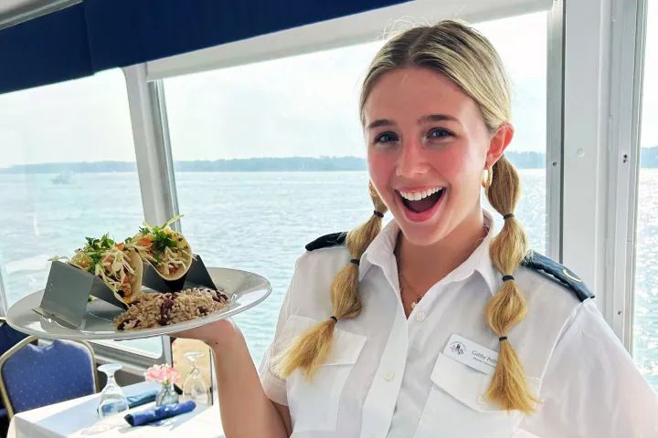 a woman smiling next to a body of water