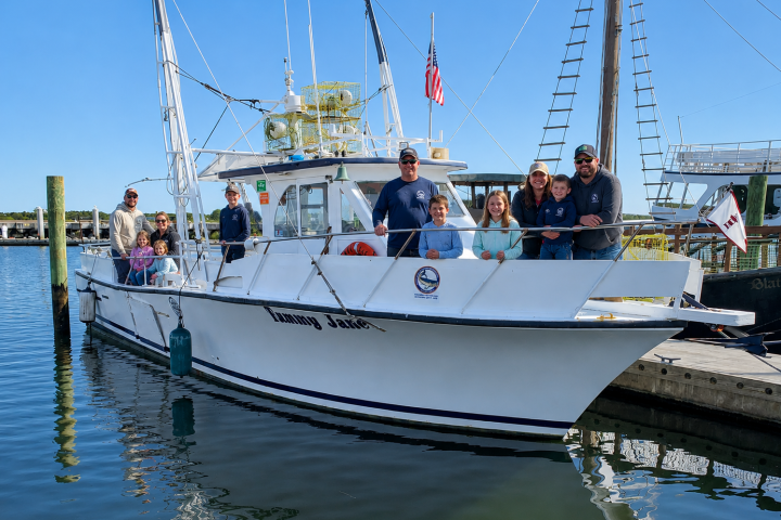 Group of people on a boat docked at a marina on a sunny day.