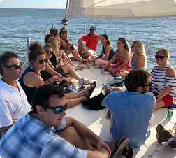 Group of people sitting on a sailboat in sunny weather.