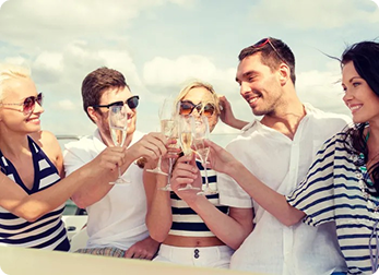 Group of five people in summer attire clinking glasses on a boat.