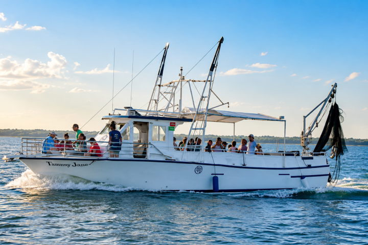 A boat with people on a sunny day, cruising on the water.