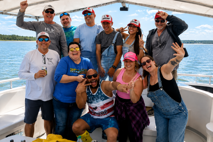 Group of eleven people smiling on a boat under a canopy.