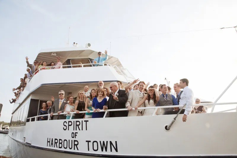Group of people on a boat named 'Spirit of Harbour Town' waving and smiling.