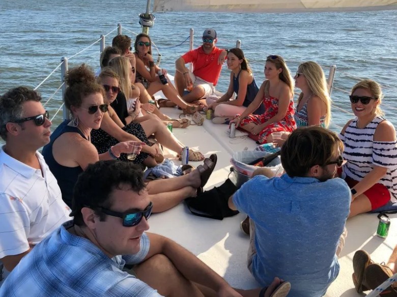 Group of people seated on a sailboat in sunny weather.