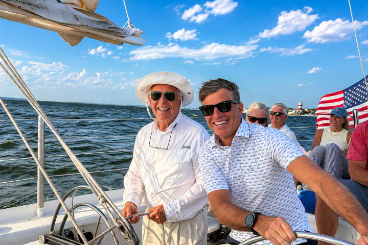 Group of people smiling on a sailing boat with an American flag.