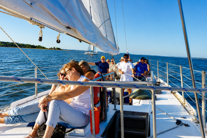 People relaxing on a sailboat under clear blue skies.